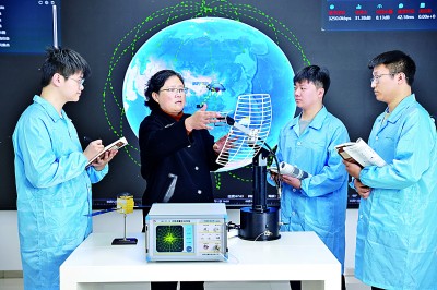     重庆电子科技职业大学通信工程学院院长陶亚雄（左二）给学生讲解学校和卫星企业联合搭建的空天地一体化组网架构。资料图片
