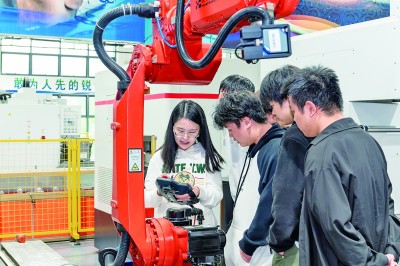     重庆工业职业技术学院教师曲伟（左一）为学生上机器人实训课。资料图片
