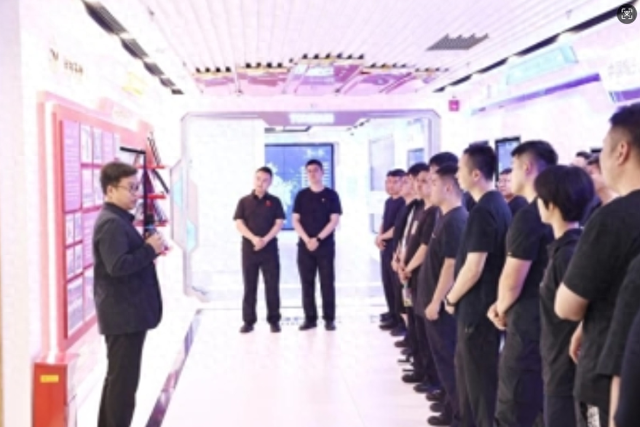 董纪伟(左一)为丰台公安分局团委一行讲解企业展厅